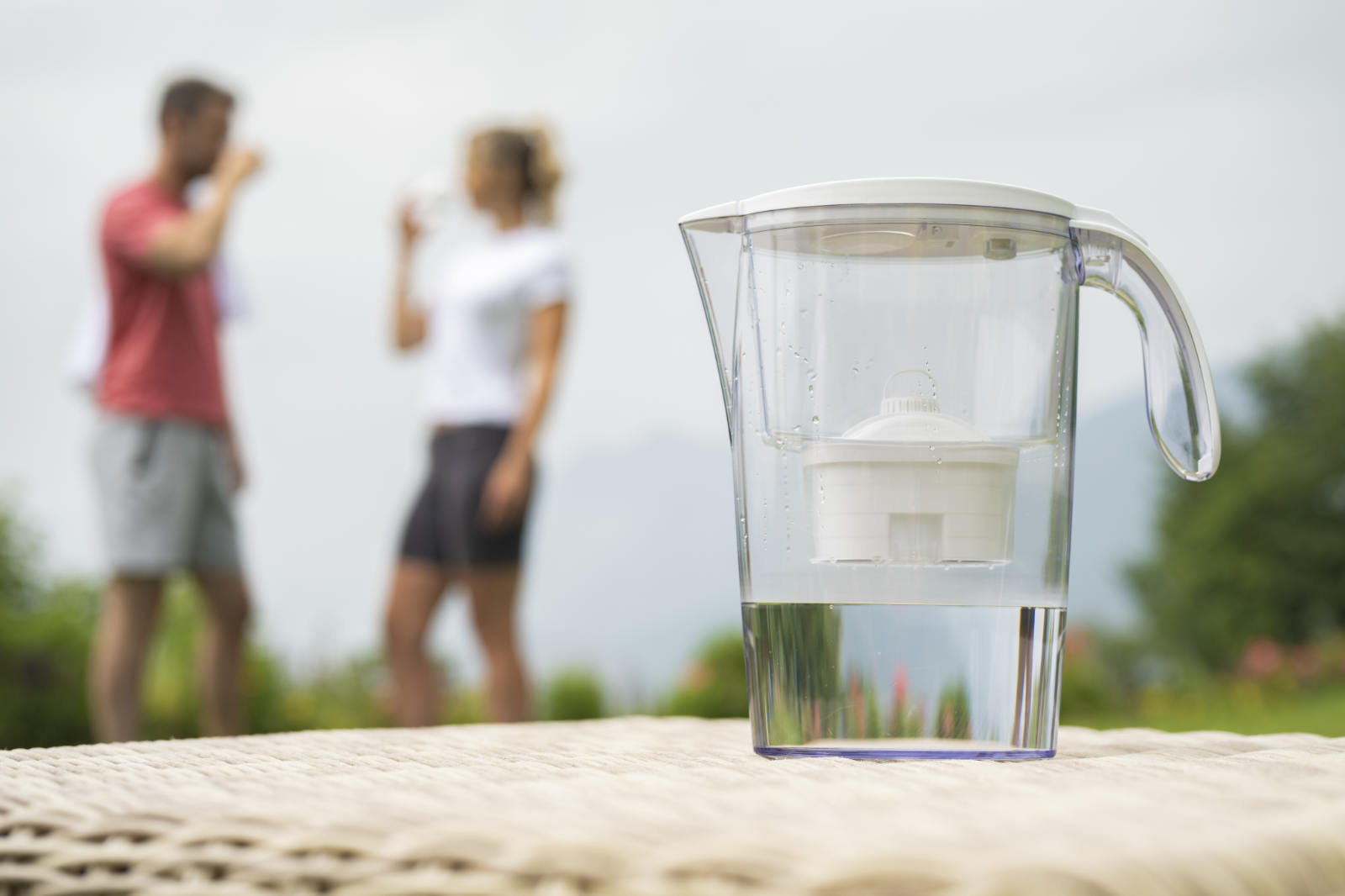 Laica Filterkanne mit Menschen im Hintergrund, die Wasser trinken